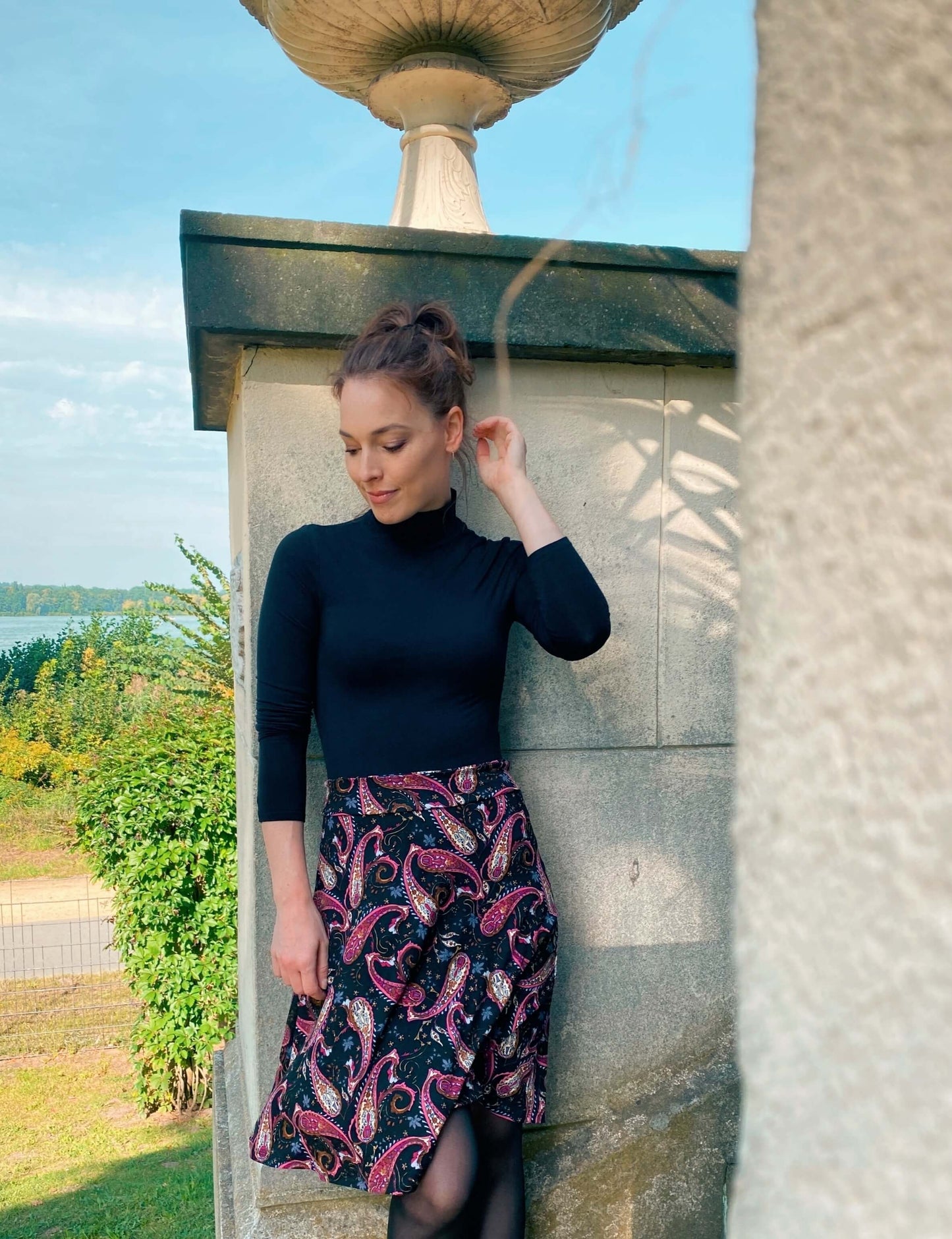 Frau in einem knielangen, schwarzen Jerseyrock in A-Linie mit Paisleymuster - LA.LUKA Berlin