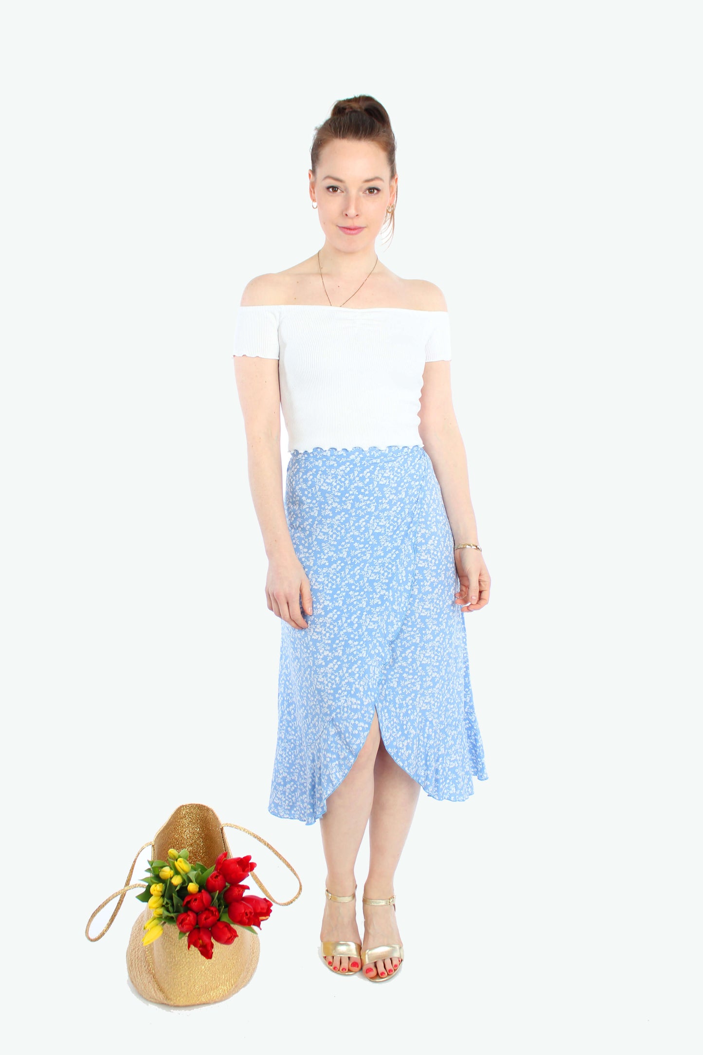 Frau, in einem hellblauen Wickelrock in Midilänge mit weißen Blümchen und Volant. Der Midiock besteht aus luftigen Viskose.