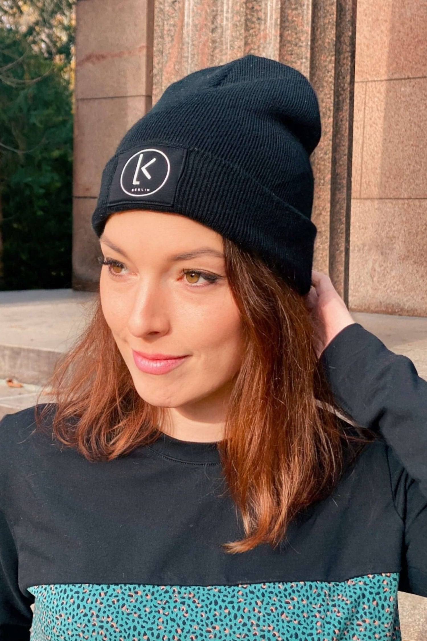 Frau, trägt eine schwarze Mütze mit LA.LUKA Berlin Logo von LA.LUKA Berlin.