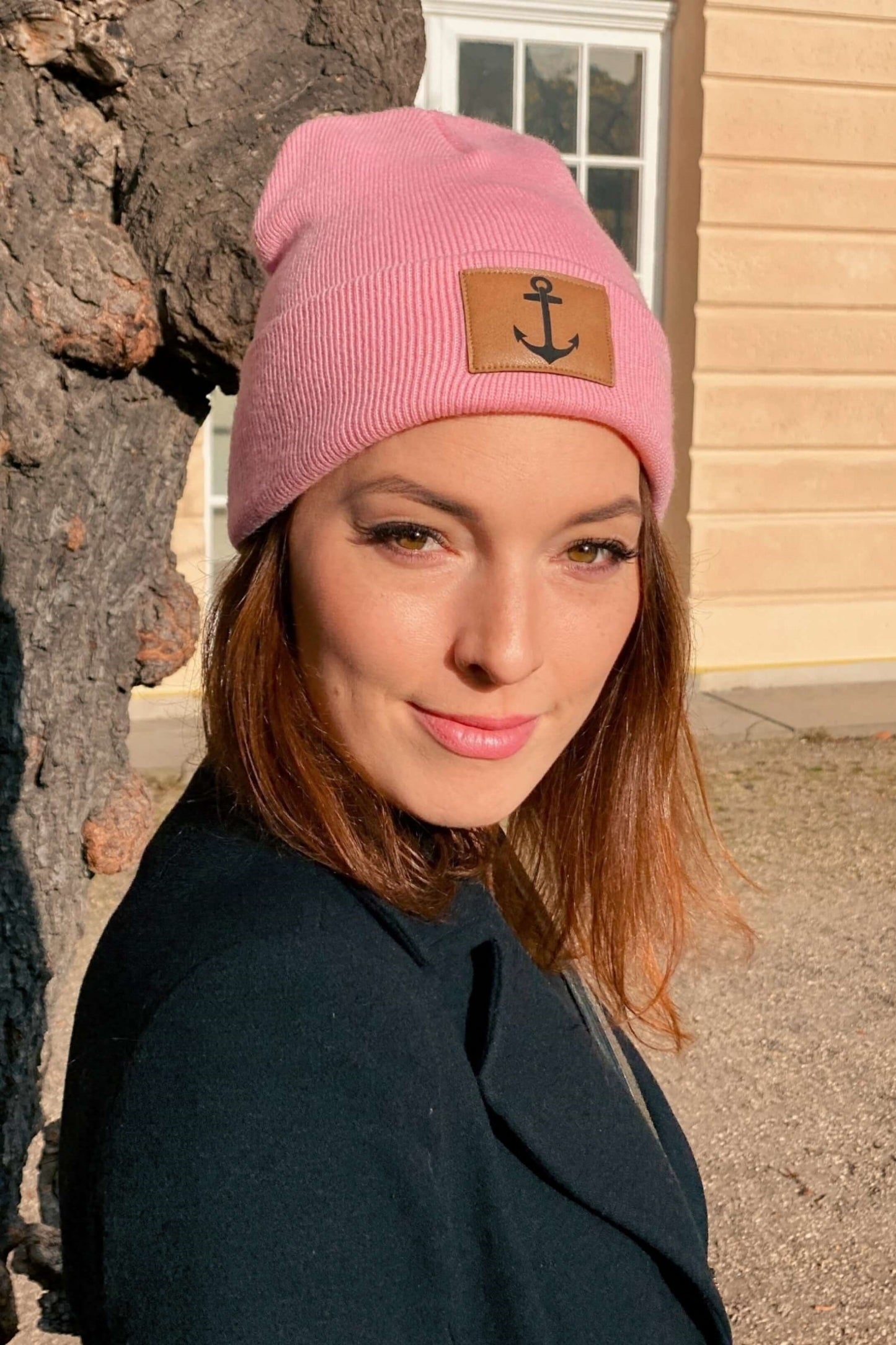 Frau, trägt eine Mütze in rosa mit Aufnäher und Anker-Motiv.