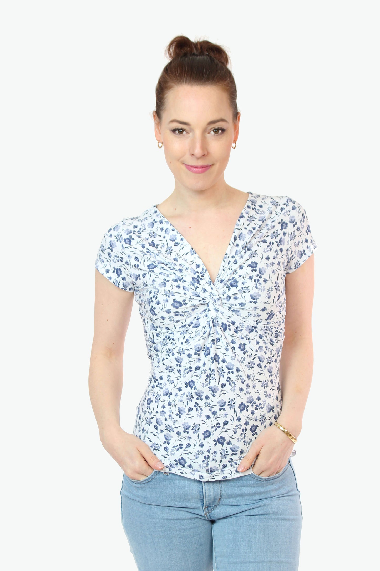 Frau in einem weißen Knotenshirt mit blauen Blumen und kurzen Ärmeln von LA.LUKA Berlin.