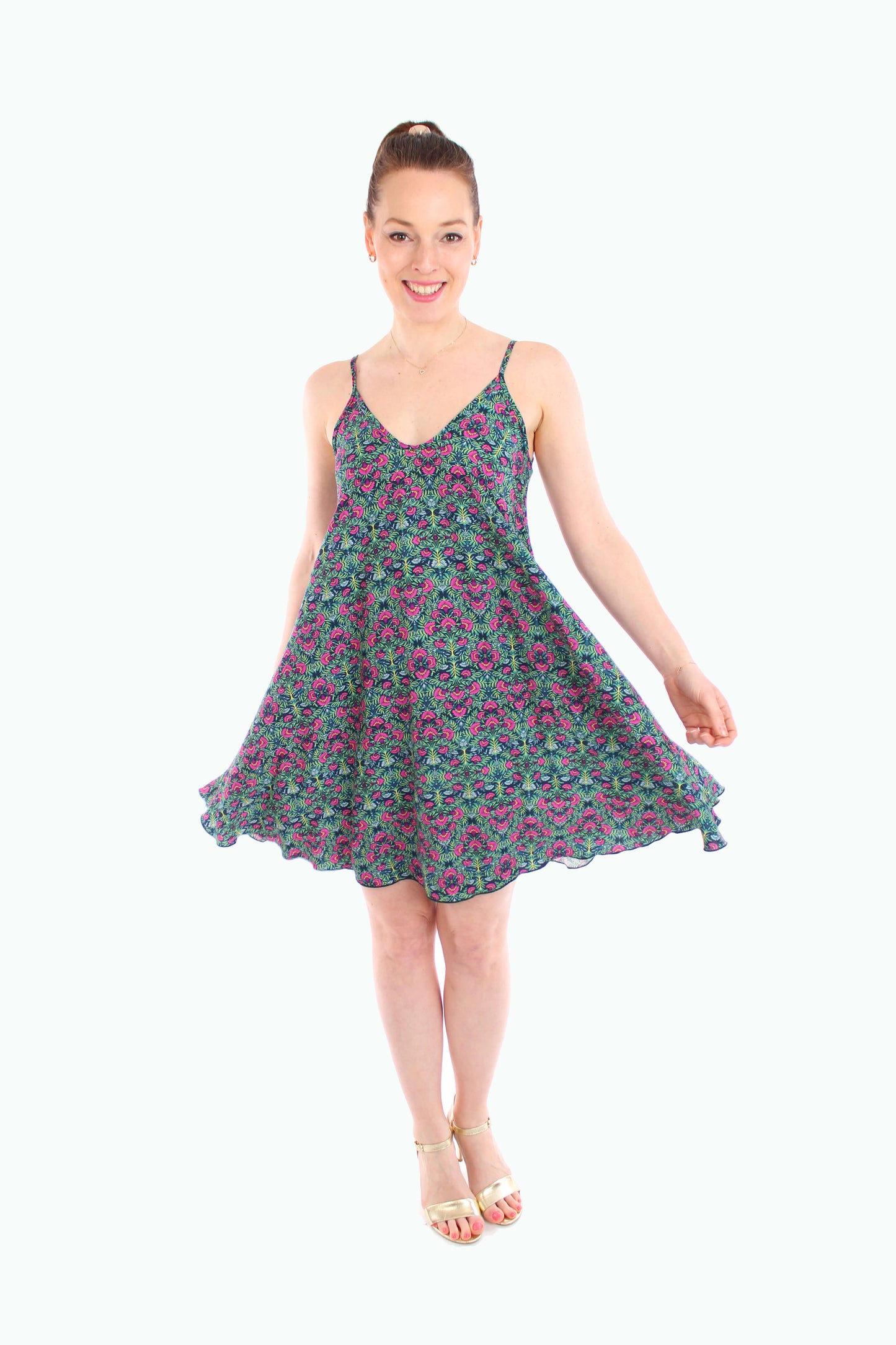 Frau trägt ein schwingendes, geblümtes Sommerkleid in Grün mit Spaghettiträgern – ideal für warme Tage und ein feminines Outfit.