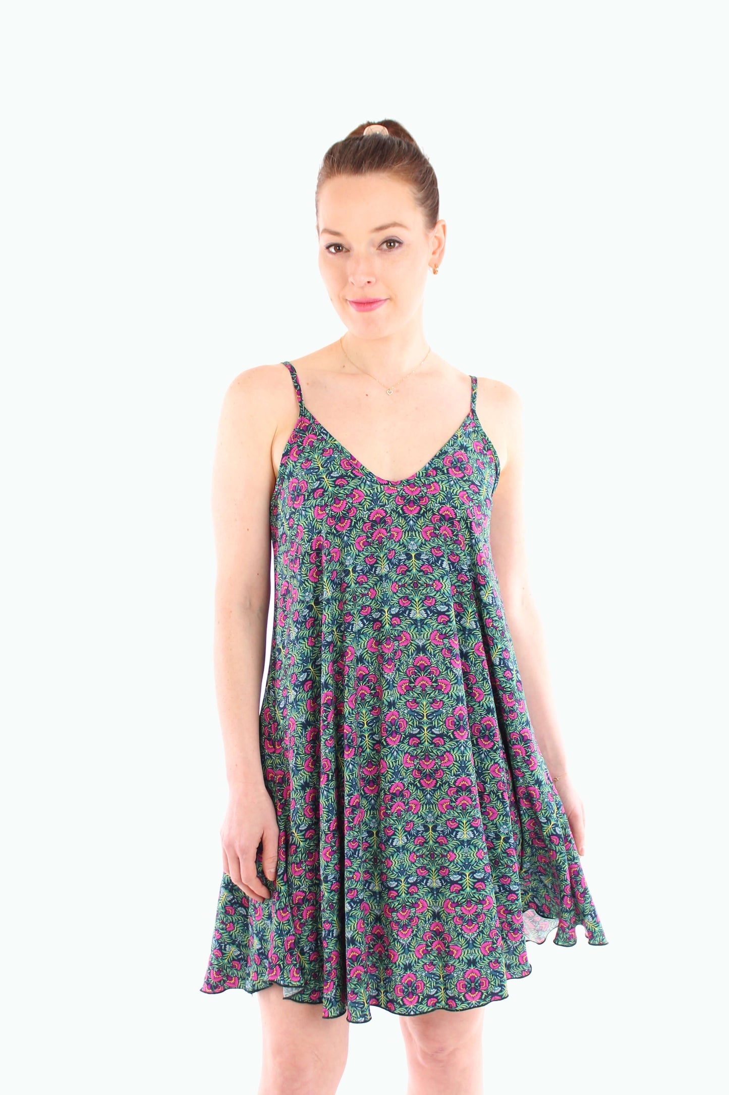 Model trägt ein luftiges, geblümtes Sommerkleid in Grün mit Spaghettiträgern und schwingendem Schnitt – ideal für warme Tage und ein feminines Outfit.