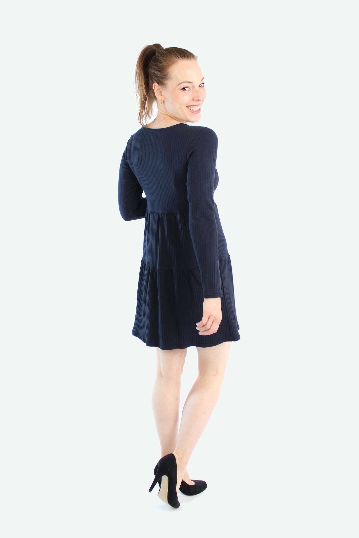 Rückansicht des dunkelblauen Stufenkleids mit Stufen-Design und schwingendem Saum.