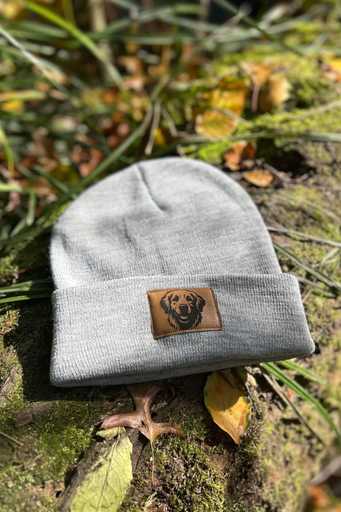 Graue Mütze von LA.LUKA Berlin mit Kunstlederpatch und Motiv eines Labradors, liegend auf Holz – stilvolles Hunde-Accessoire für kalte Tage.