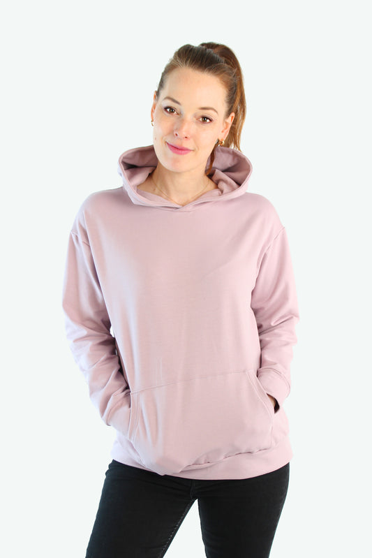 Frau trägt blushfarbenen LA.LUKA Hoodie mit Kapuze und Kängurutasche vor hellem Hintergrund – fair produziert in Berlin.