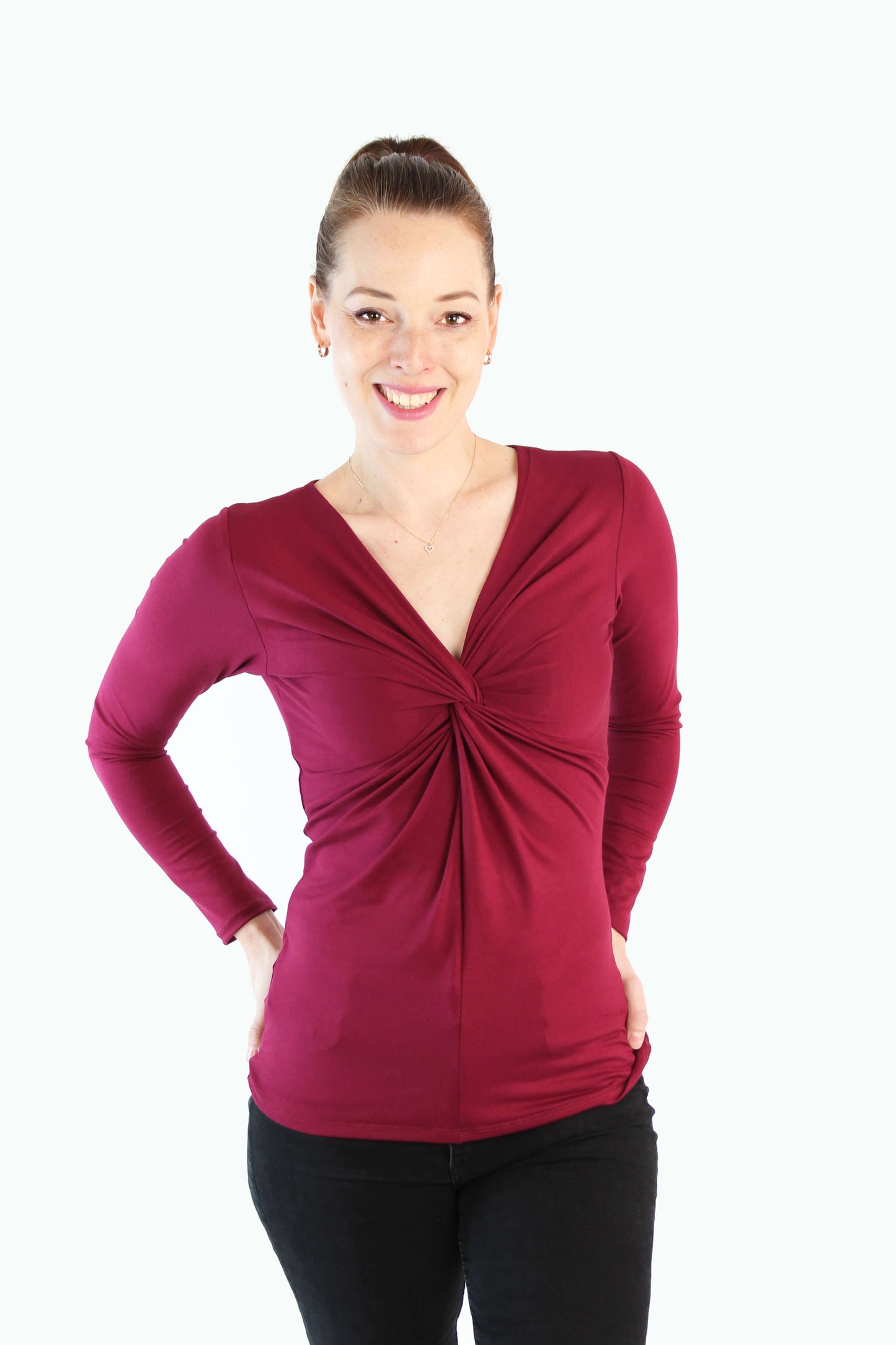 Model trägt bordeauxfarbenes Longsleeve mit Twist-Detail und V-Ausschnitt von LA.LUKA Berlin, auf hellem Hintergrund – stylisch, feminin & fair produziert.