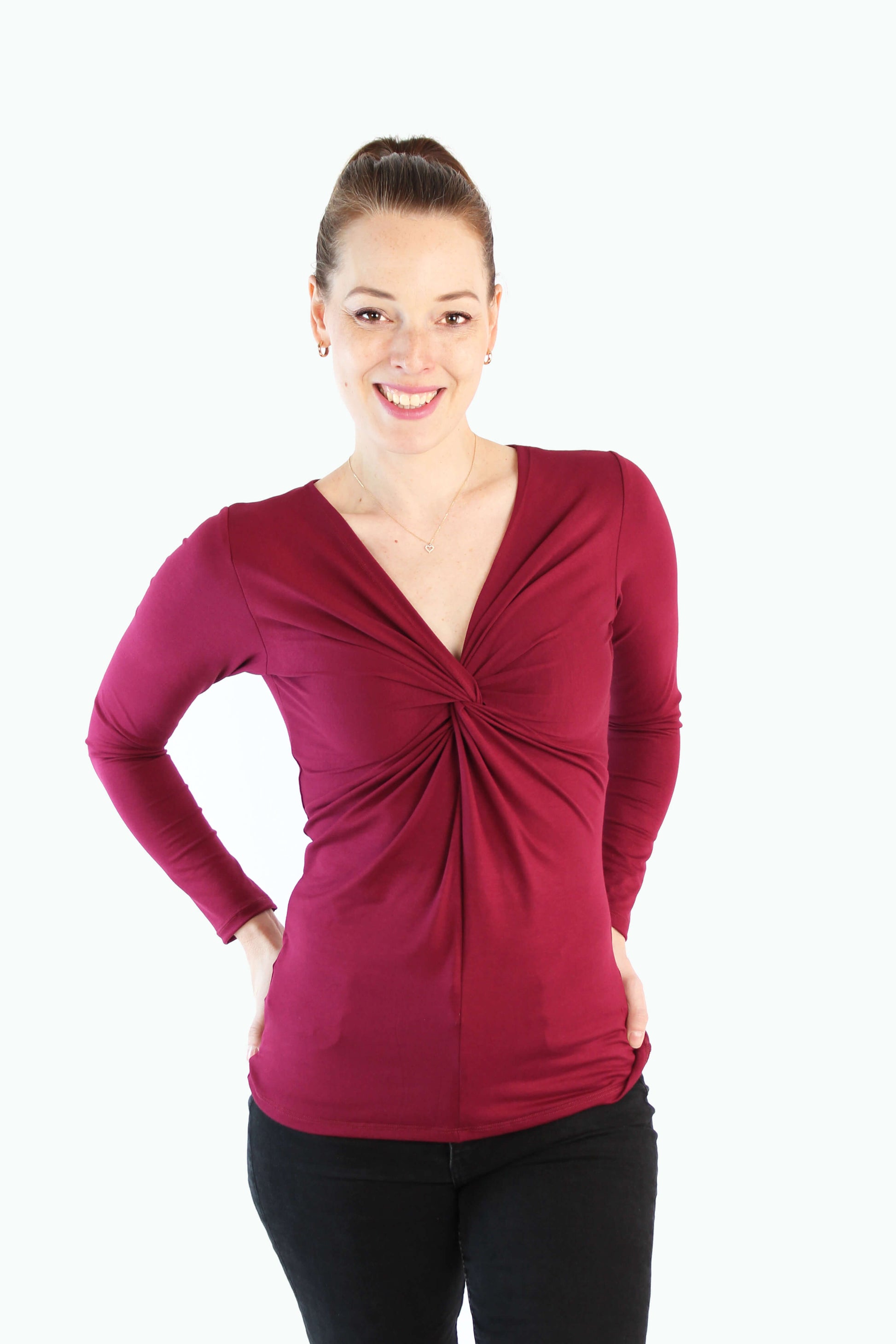 Model trägt bordeauxfarbenes Longsleeve mit Twist-Detail und V-Ausschnitt von LA.LUKA Berlin, auf hellem Hintergrund – stylisch, feminin & fair produziert.