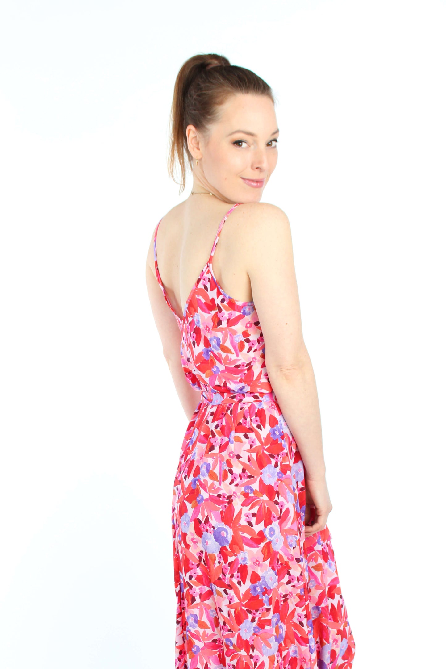 Frau, in einem Sommerkleid in Midilänge in rot/rosé geblümt mit Spaghettiträgern aus leichtem Viskosestoff von LA.LUKA Berlin.
