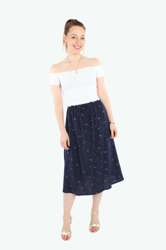 Frau, in einem eleganten, dunkelblauen Midirock mit kleinen, goldenen Punkten von LA.LUKA Berlin. 