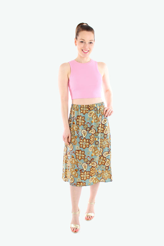 Midirock mit Paisley-Muster in Mintgrün, getragen von einem Model mit pinkem Crop-Top und goldenen Sandalen.