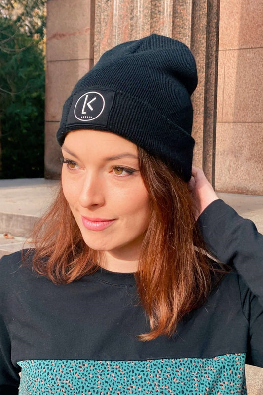 Frau, trägt eine schwarze Mütze mit LA.LUKA Berlin Logo von LA.LUKA Berlin.