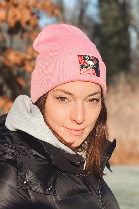 Frau trägt eine rosa Mütze mit Flamingo-Motiv, im Hintergrund Bäume.