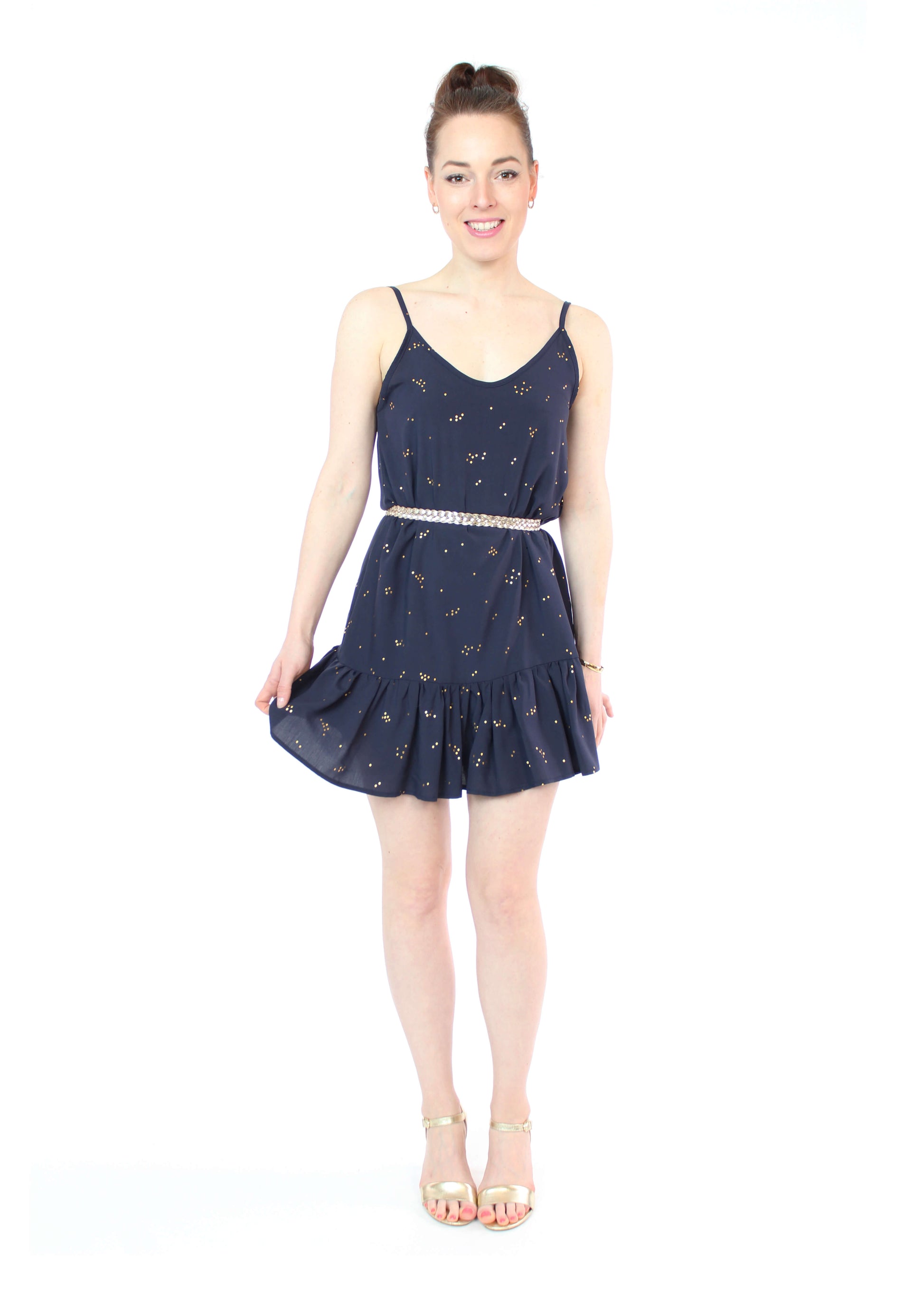 Model, in einem kurzen Trägerkleid in dunkelblau mit goldenen Punkten und Volants am Saum aus Viskose von LA.LUKA Berlin.