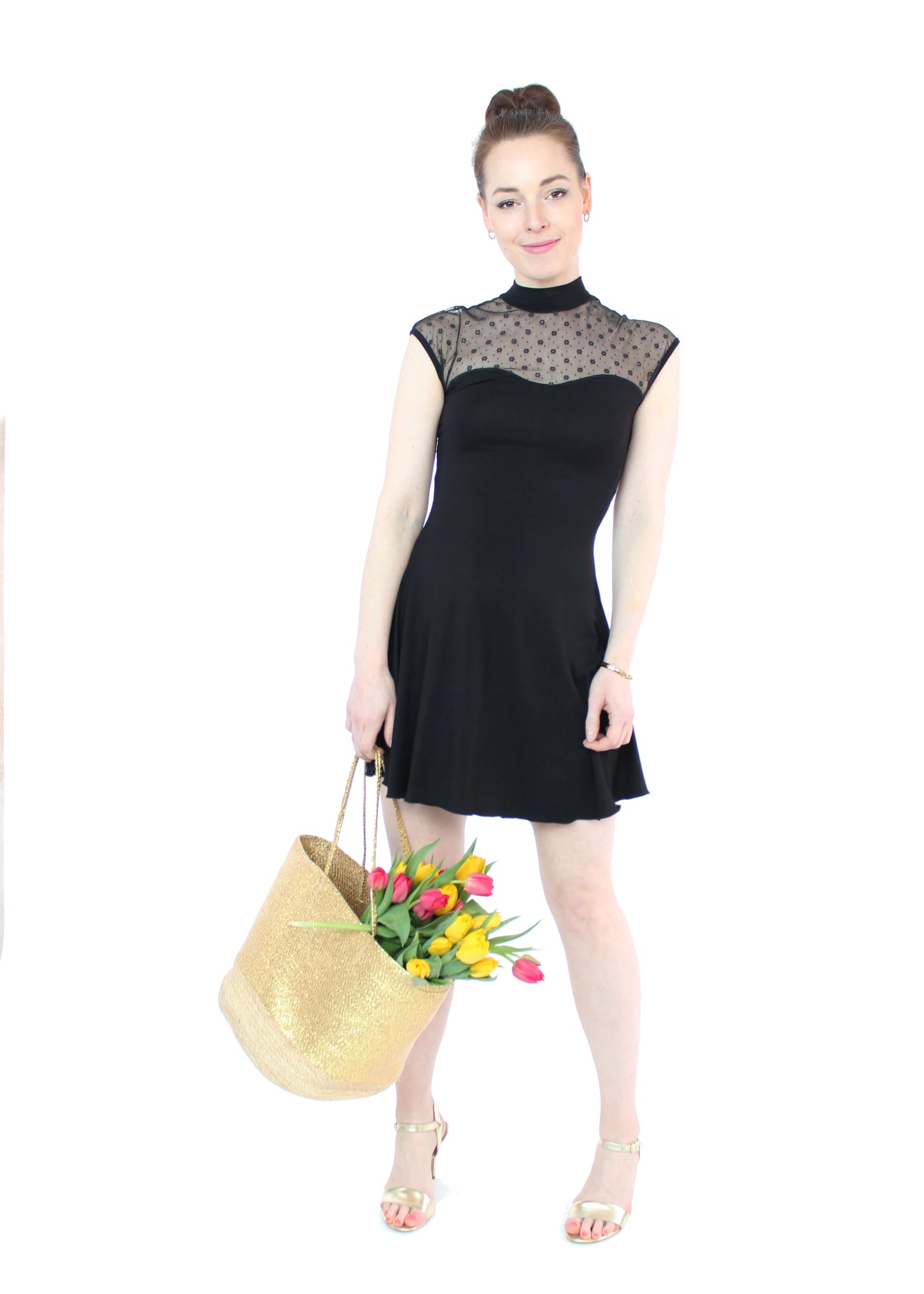 Frau, in einem eleganten, schwarzen Minikleid mit Blümchen Tüll und Stehkragen in schwarz aus Viskosejersey von LA.LUKA Berlin. Sie trägt eine Tasche mit Tulpemn.