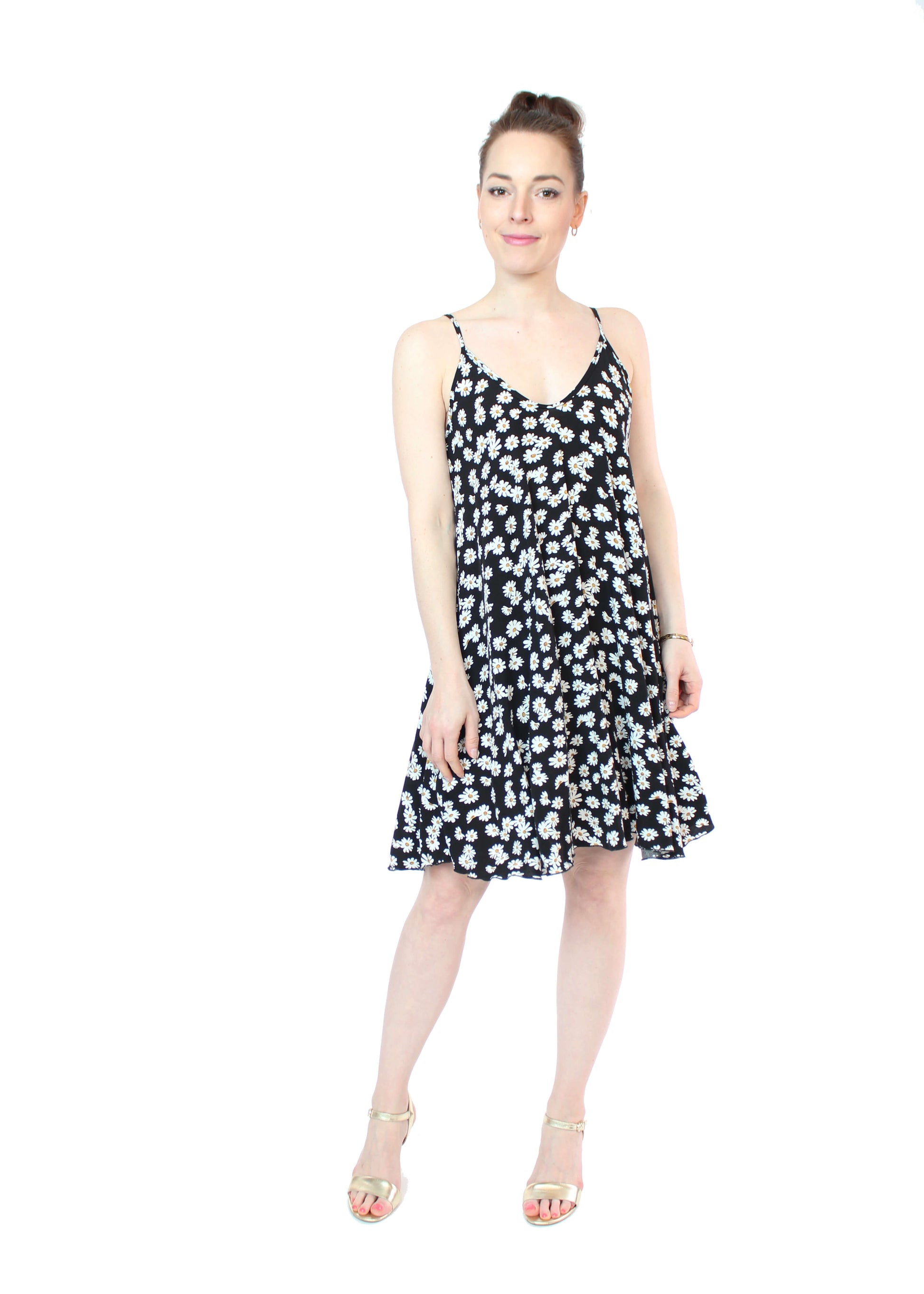 Frau trägt ein florales Trägerkleid in Schwarz mit weißen Gänseblümchen – leichtes Sommerkleid für Urlaub, Alltag oder Gartenparty.