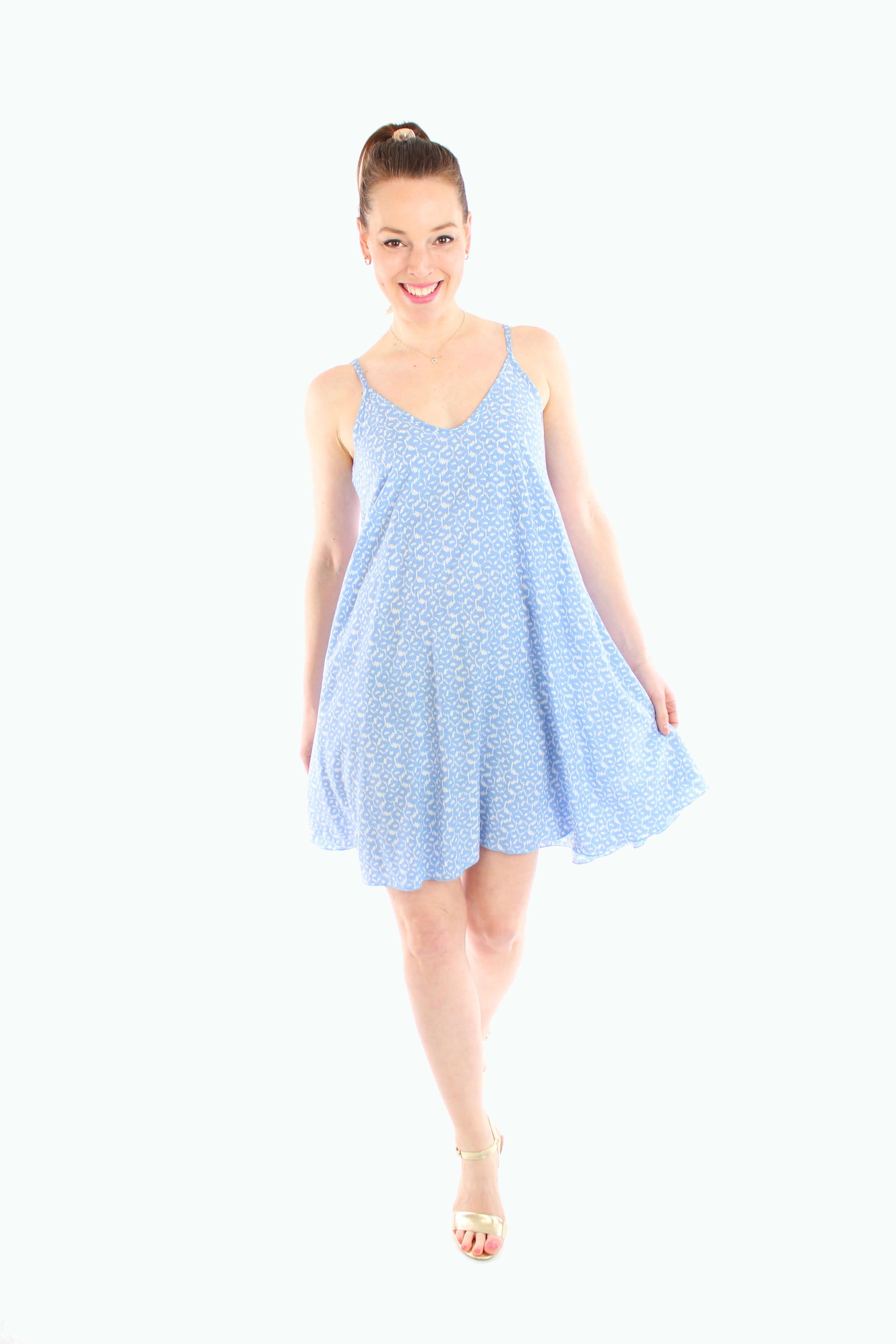 Frau trägt ein leichtes, blau gemustertes Minikleid mit Spaghettiträgern und V-Ausschnitt – ideal als Sommerkleid oder Strandkleid.