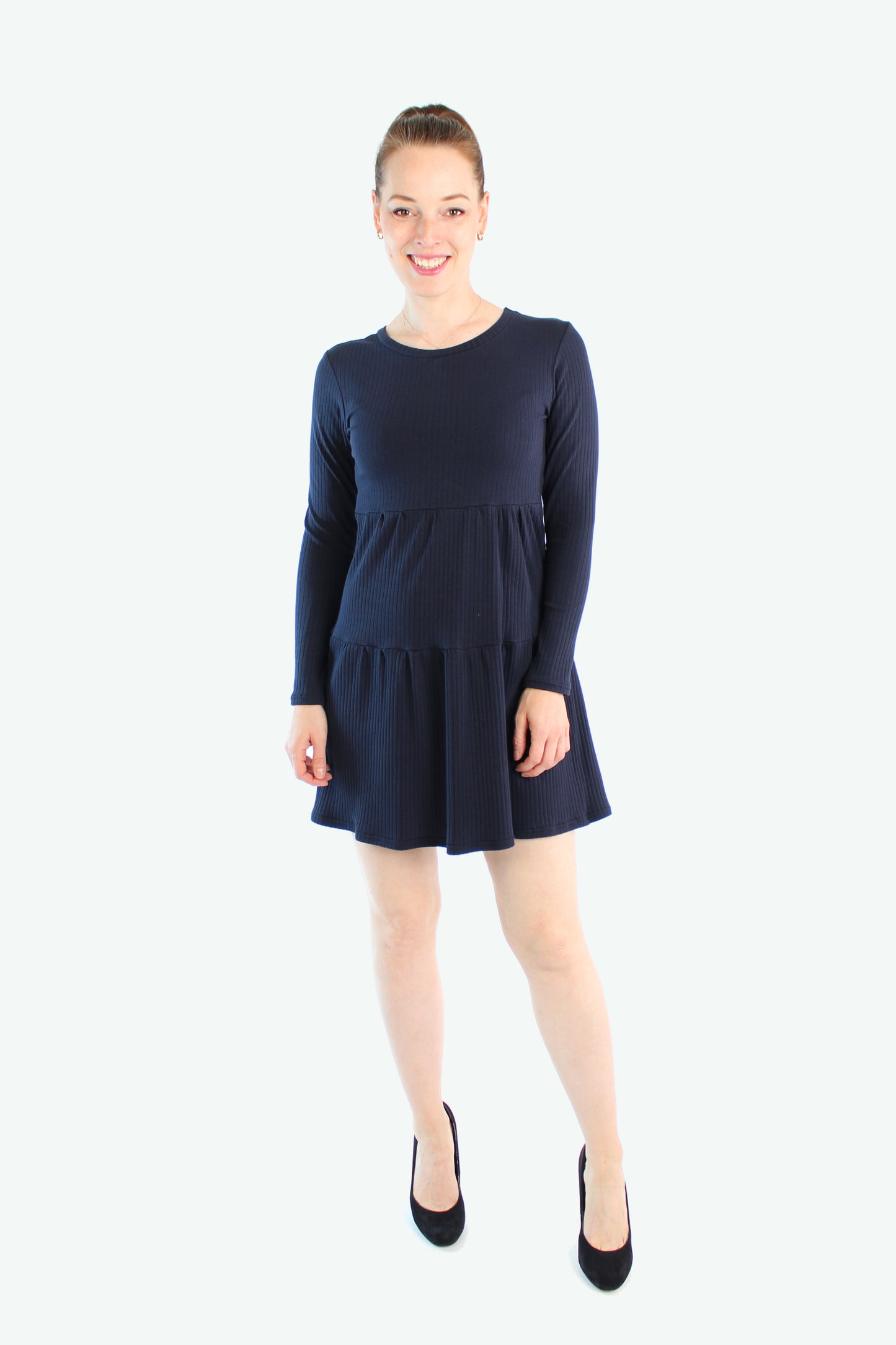 Dunkelblaues Stufenkleid aus Rippjerseys aus Baumwolle,  getragen von einem Model mit schwarzen Pumps, Vorderansicht.