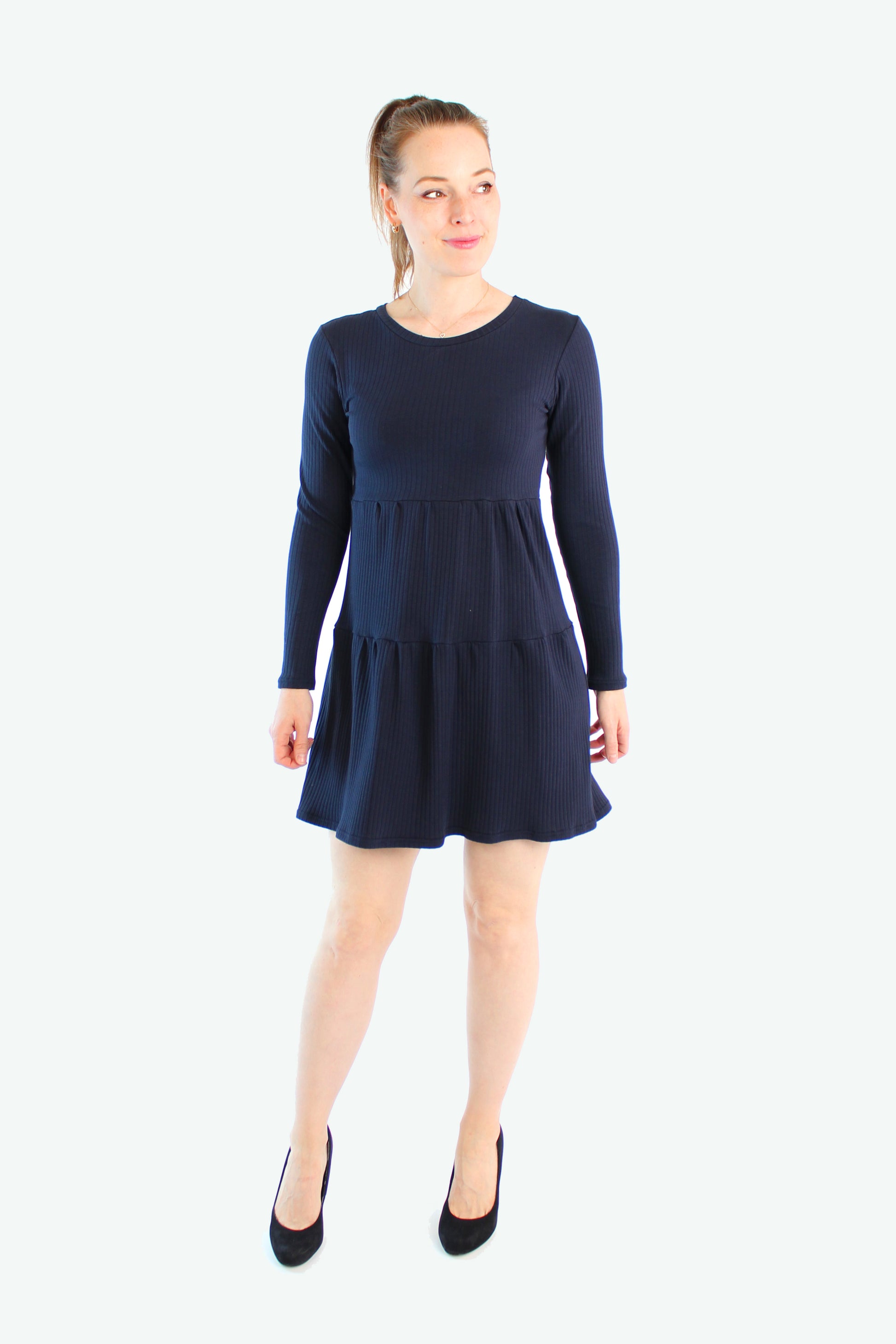 Dunkelblaues Stufenkleid aus Baumwolle, getragen von einem Model mit schwarzen Pumps, Vorderansicht.