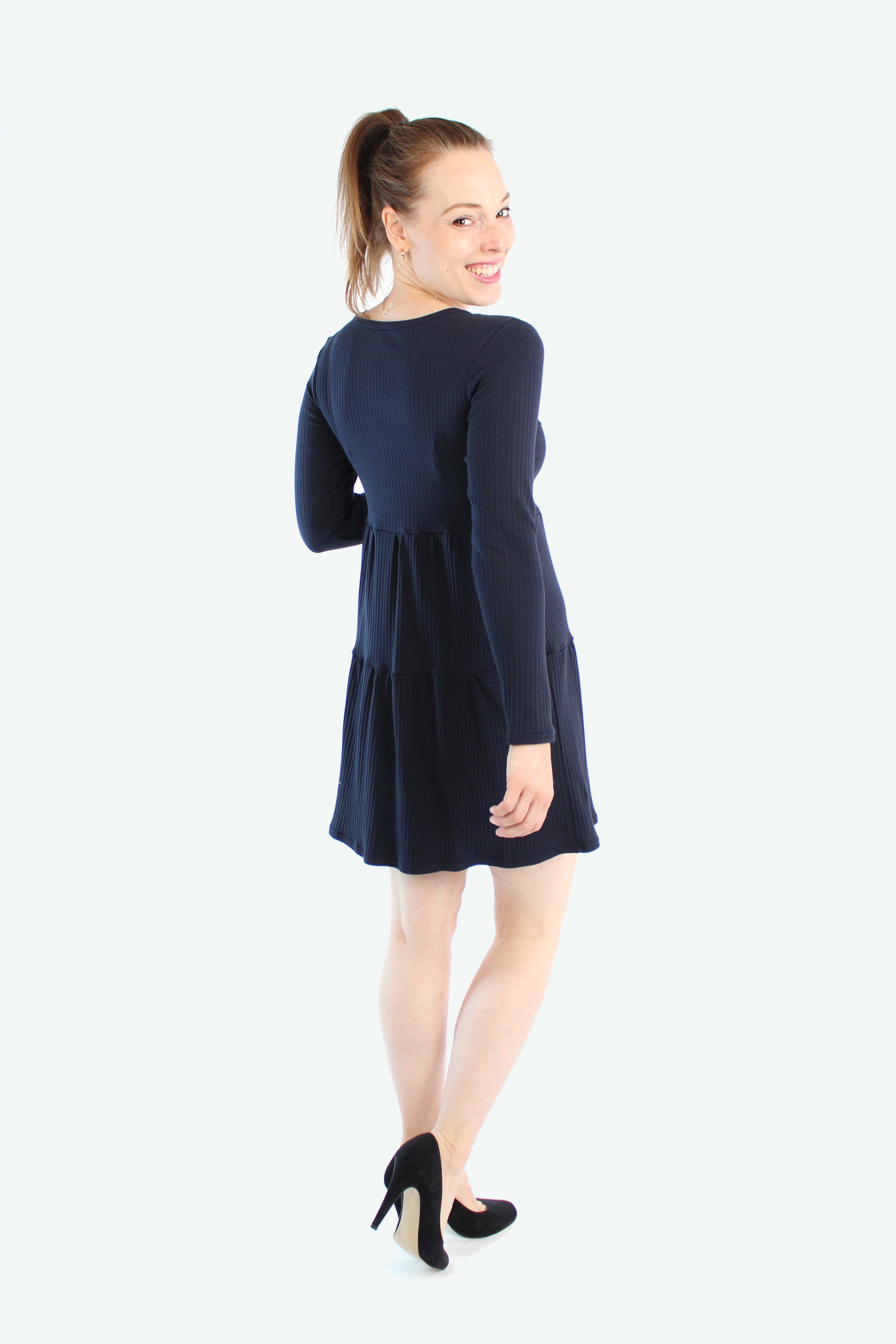 Rückansicht des dunkelblauen Stufenkleids mit Stufen-Design und schwingendem Saum.