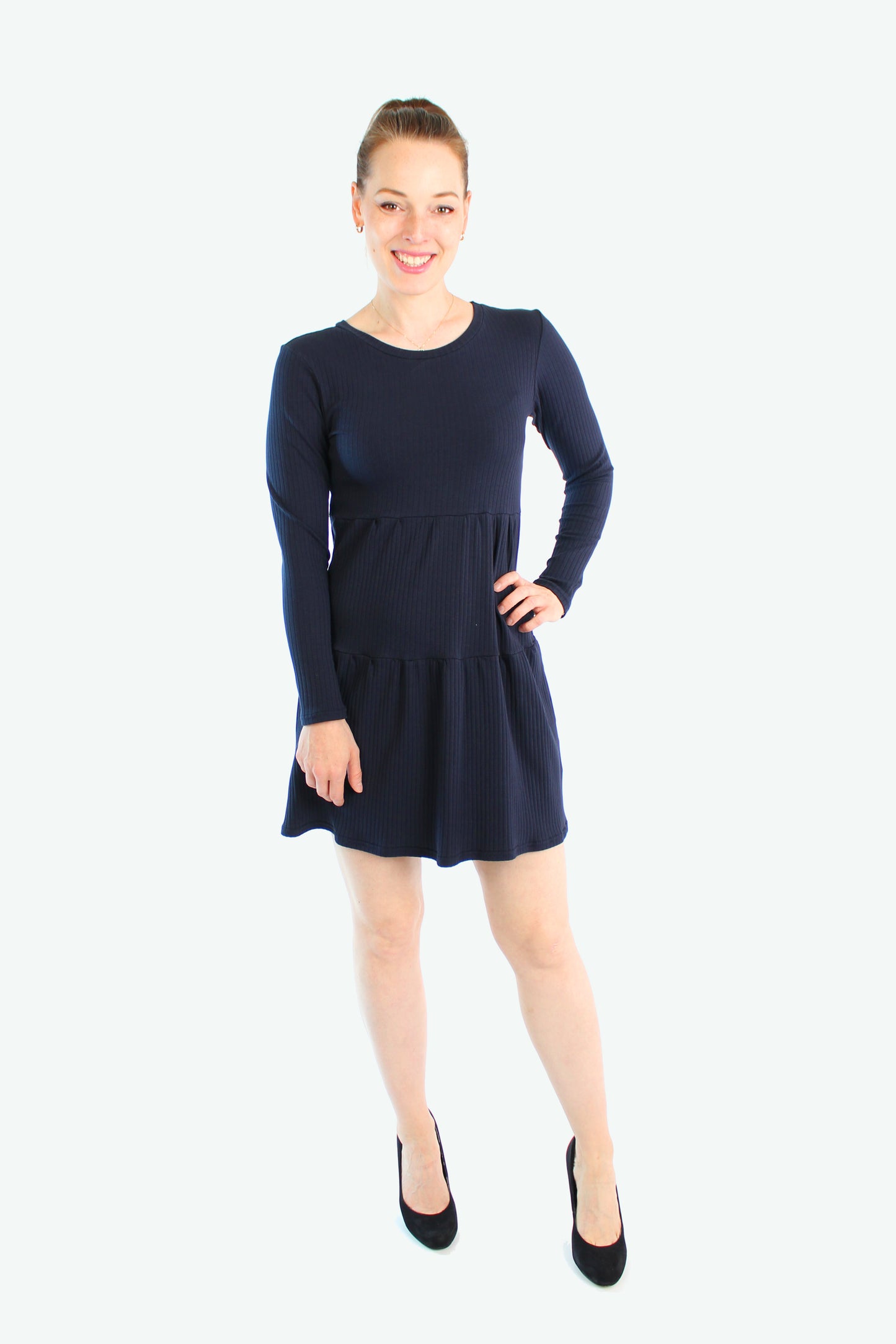 Dunkelblaues Stufenkleid mit langen Ärmeln, Model lächelt in klassischer Pose, fair produziert in Berlin.