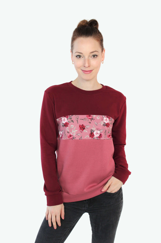 Frau, in einem Pullover in bordeaux und rosé mit Blumenmuster von LA.LUKA Berlin.