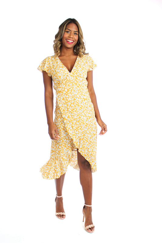 Frau in einem sommerlichen, langen Wickelkleid in gelb mit weißen Blumen und kurzen Ärmeln aus leichtem Viskosestoff von LA.LUKA Berlin.