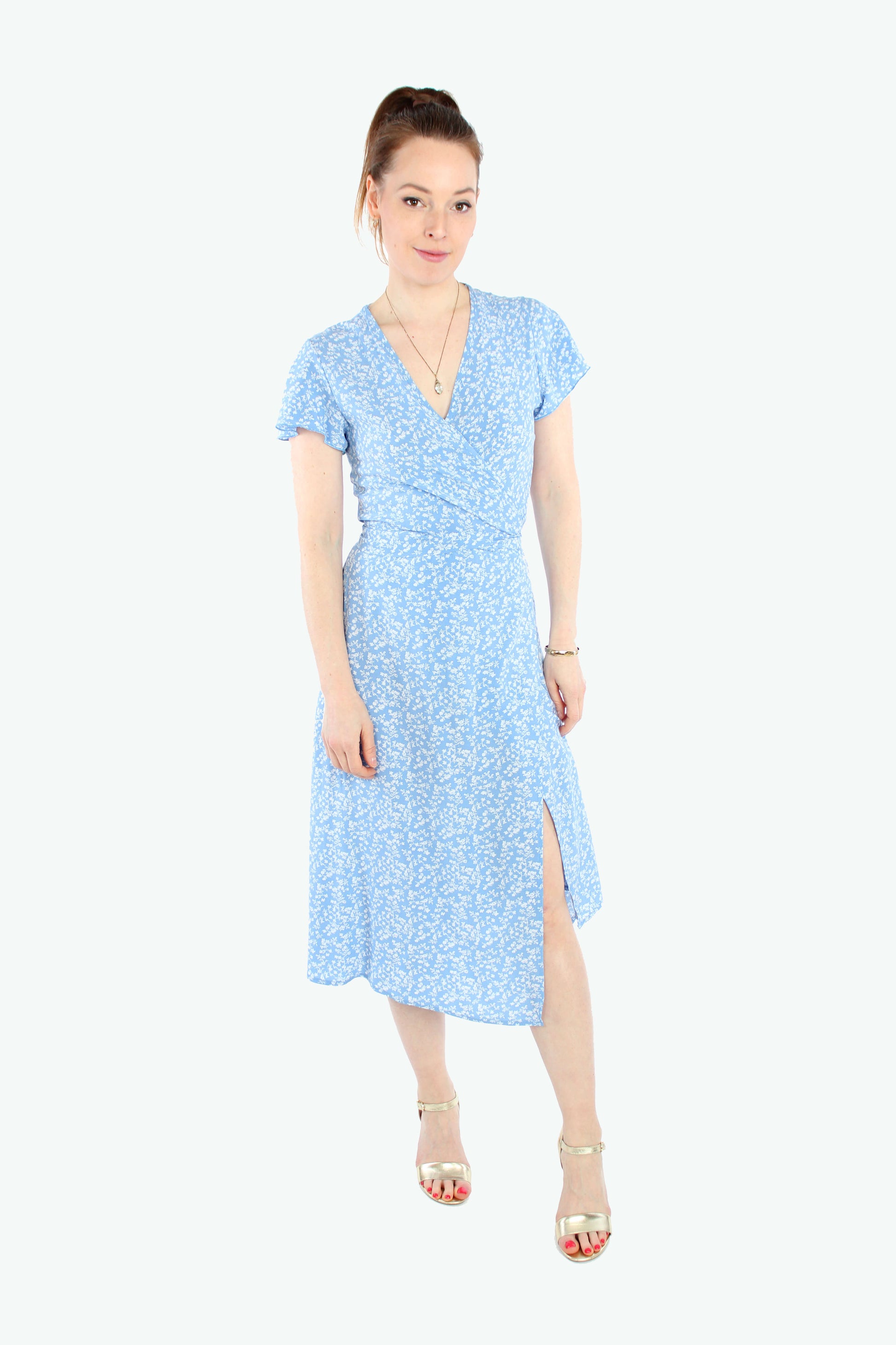 Frau in einem Sommerkleid in Midilänge zum wickeln in hellblau mit weißen Blümchenmuster aus leichtem Viskosestoff von LA.LUKA Berlin.