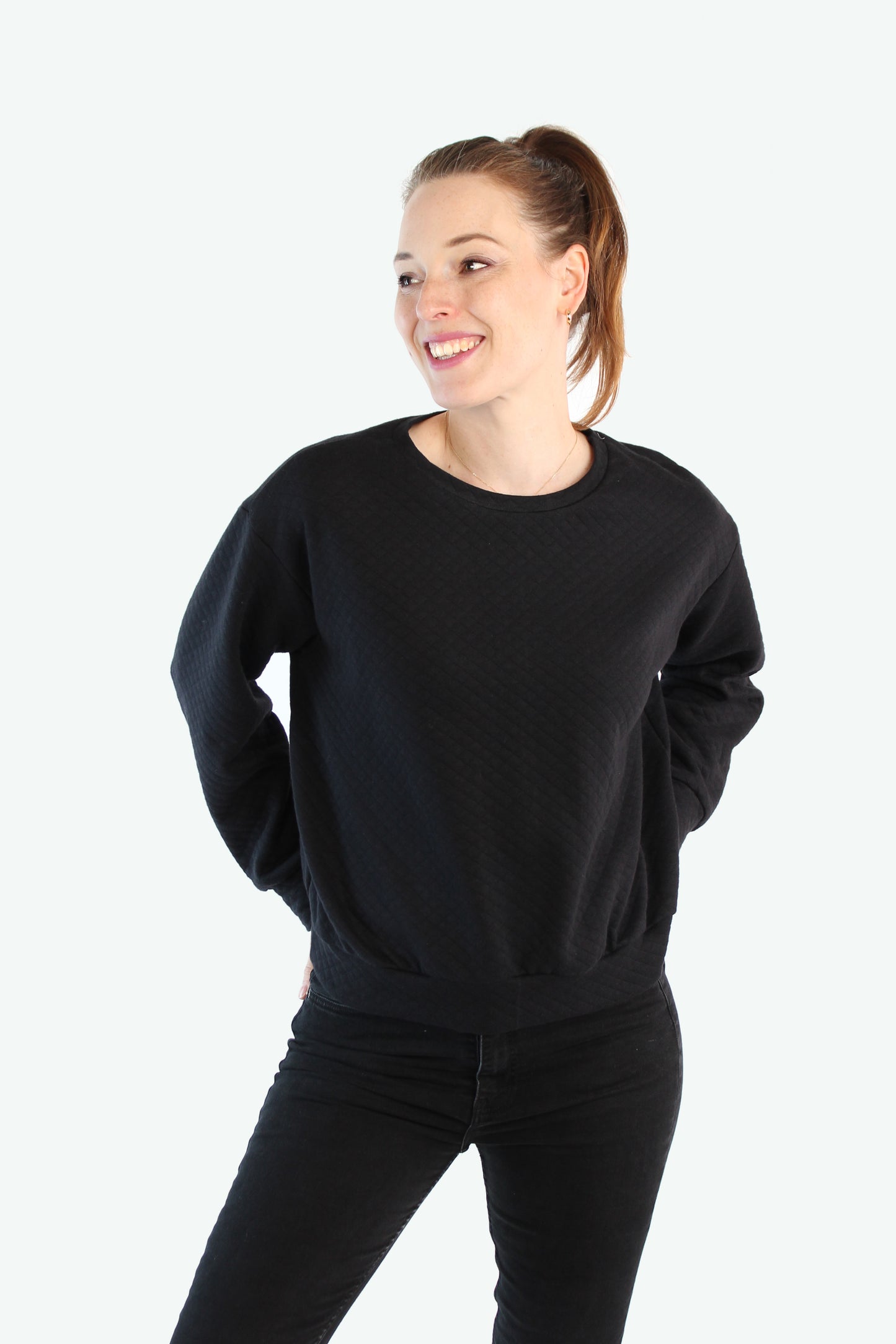 Locker geschnittener schwarzer Pullover mit dezentem Rautenmuster, Model in entspannter Bewegung – LA.LUKA Berlin.