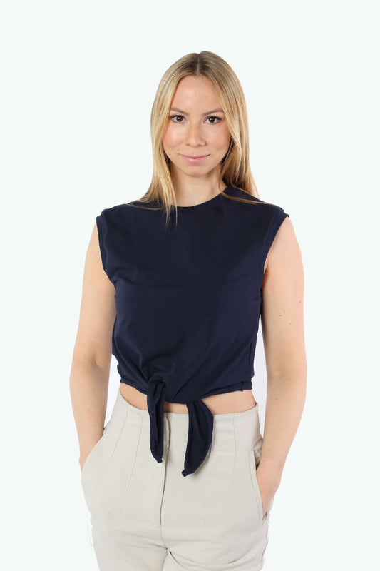 Blondes Model trägt ein Cropped T-Shirt in  dunkelblau, vorne zum Knoten, kombiniert mit einer cremefarbenen Hose.