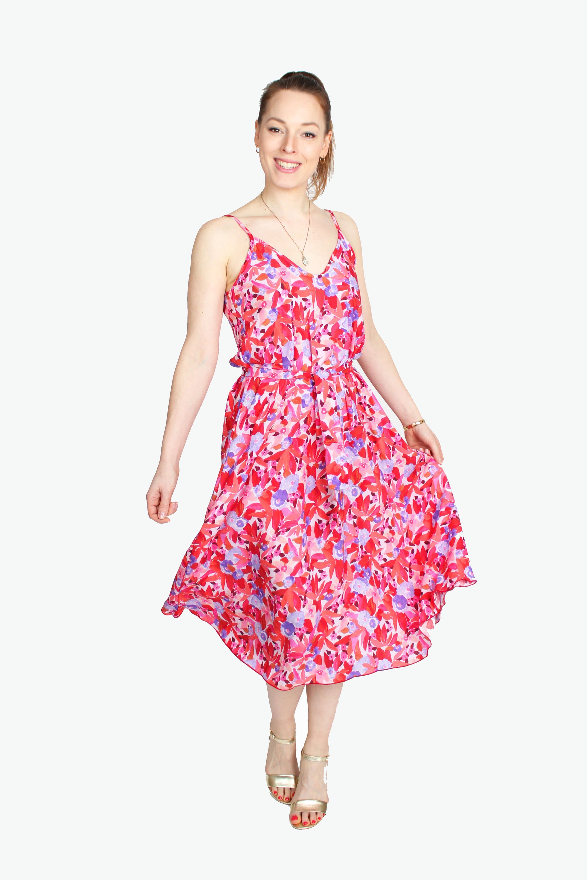 Frau, in einem Sommerkleid in Midilänge in rot/rosé geblümt mit Spaghettiträgern aus leichtem Viskosestoff von LA.LUKA Berlin.