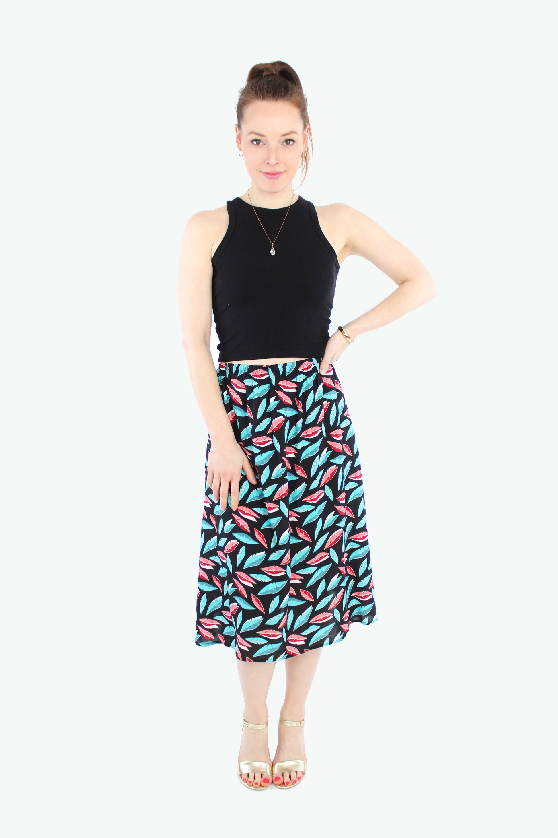 Model trägt schwarzen Midirock mit buntem Blättermuster und elastischem Bund kombiniert mit einem schwarzem Top.