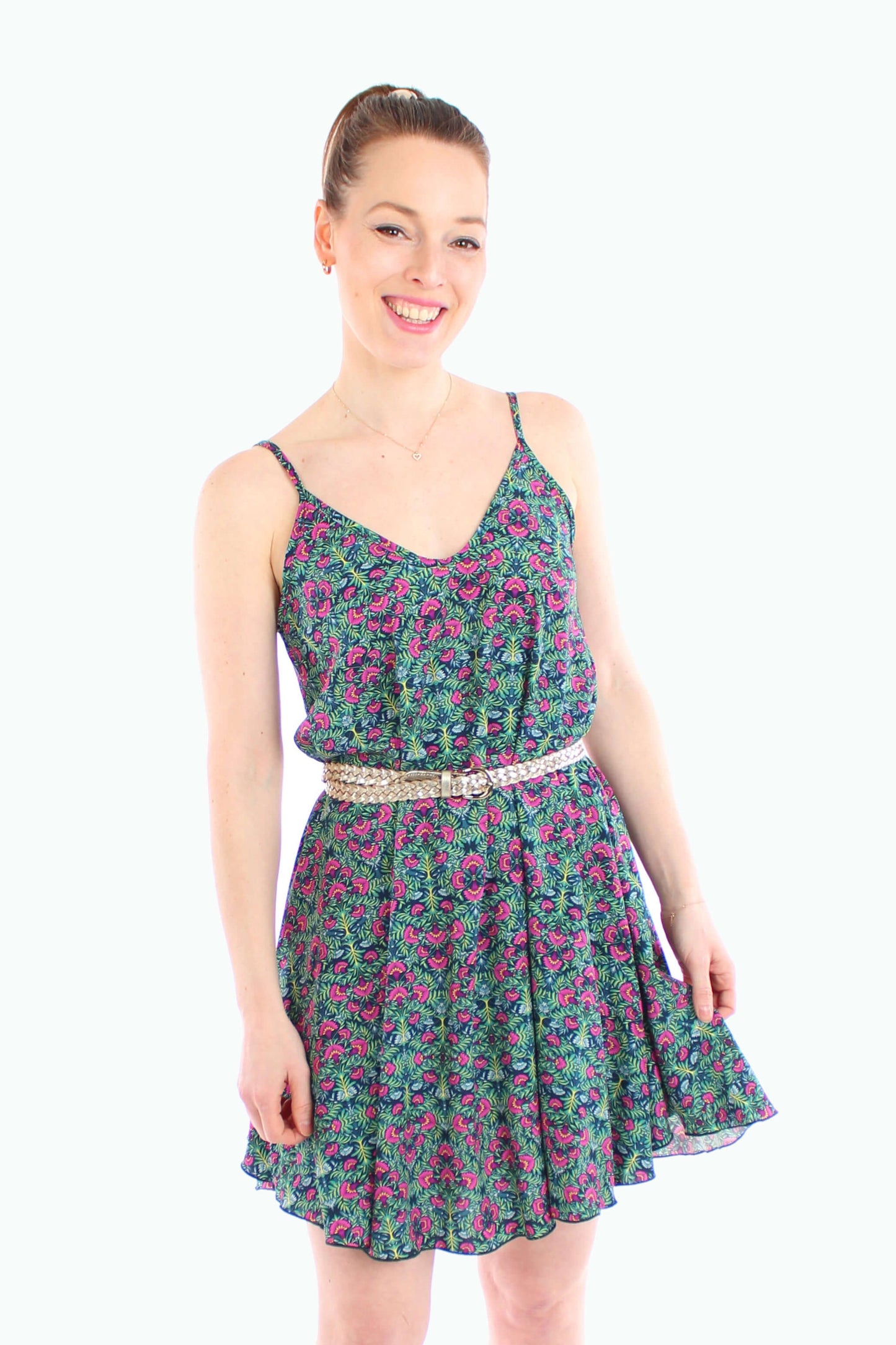 Model trägt ein luftiges, geblümtes Sommerkleid in Grün mit Spaghettiträgern und schwingendem Schnitt , kombiniert mit einem goldenen Gürtel – ideal für warme Tage und ein feminines Outfit.