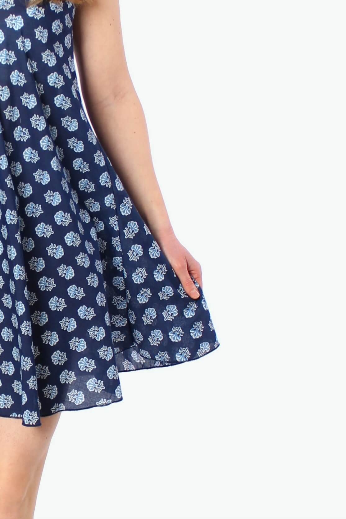 Detailansicht eines dunkelblauen Träger-Sommerkleids mit feinem hellen Blumenmuster, leichter Stoff mit weich fallendem Saum.
