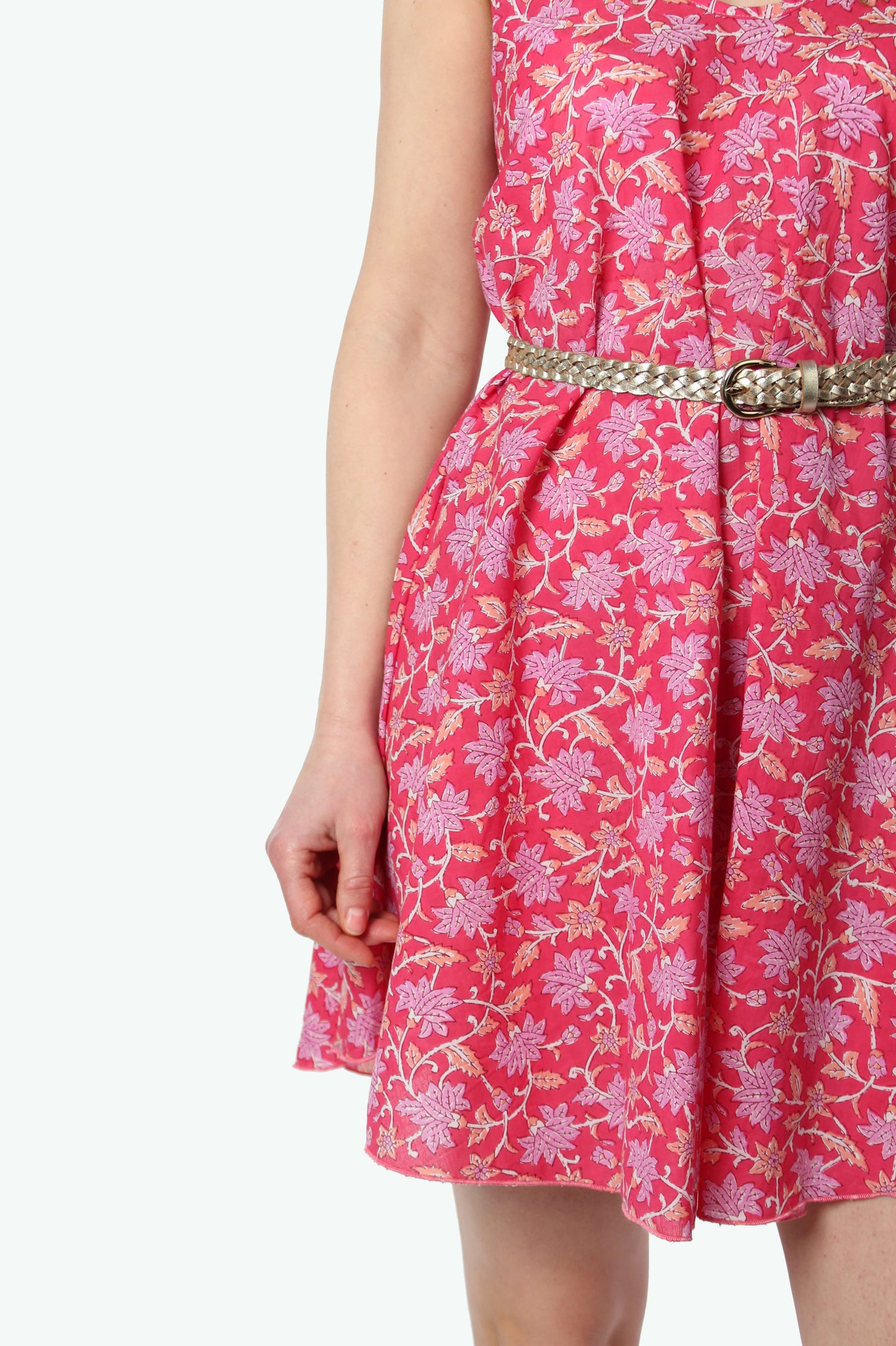 Detailaufnahme eines pink geblümten Sommerkleids aus leichtem Stoff, Taillenbereich mit geflochtenem Gürtel betont, feines florales Muster gut sichtbar.