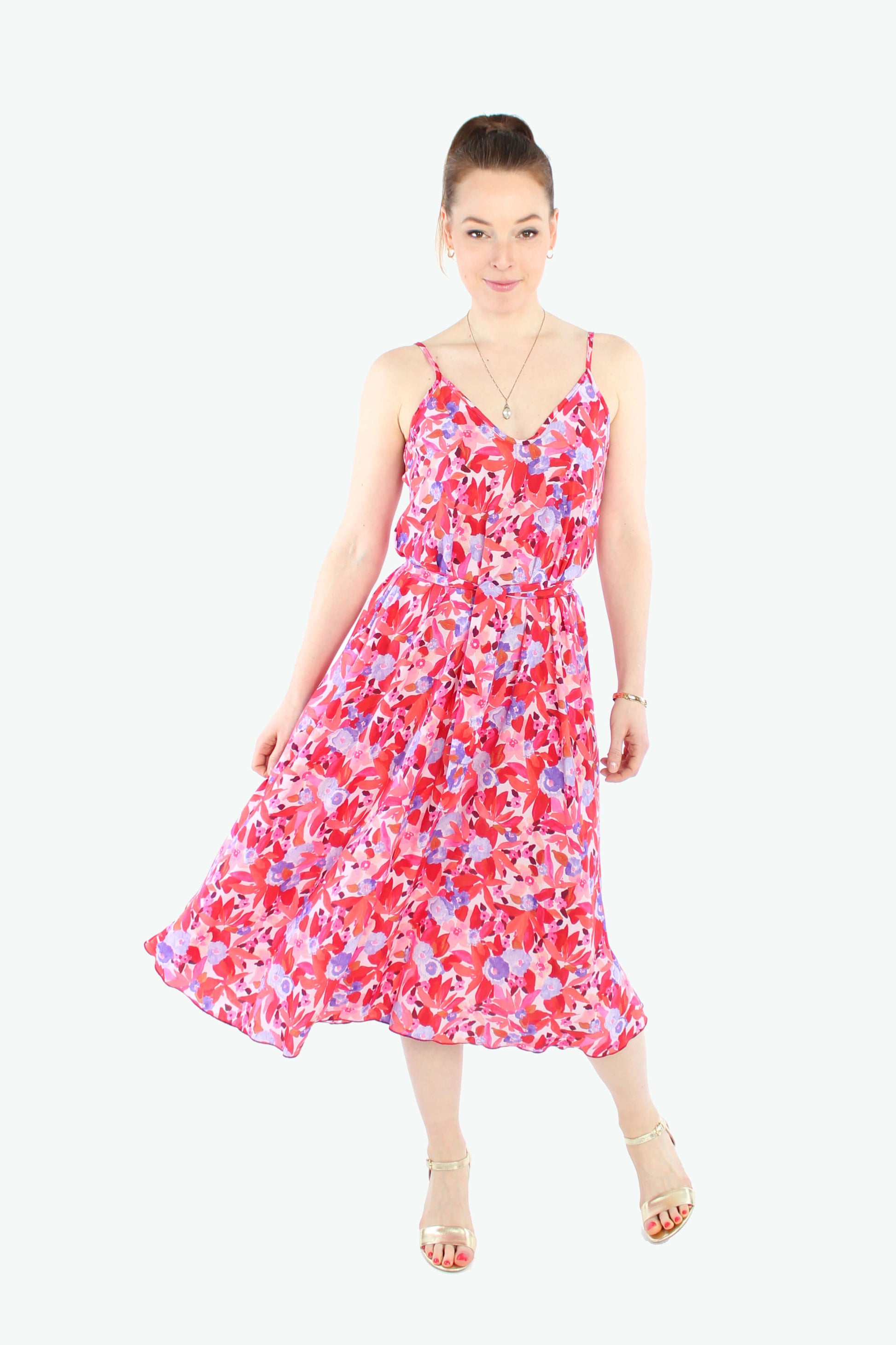 Frau, in einem schwingenden Sommerkleid in Midilänge in rot/rosé geblümt mit Spaghettiträgern aus leichtem Viskosestoff von LA.LUKA Berlin.